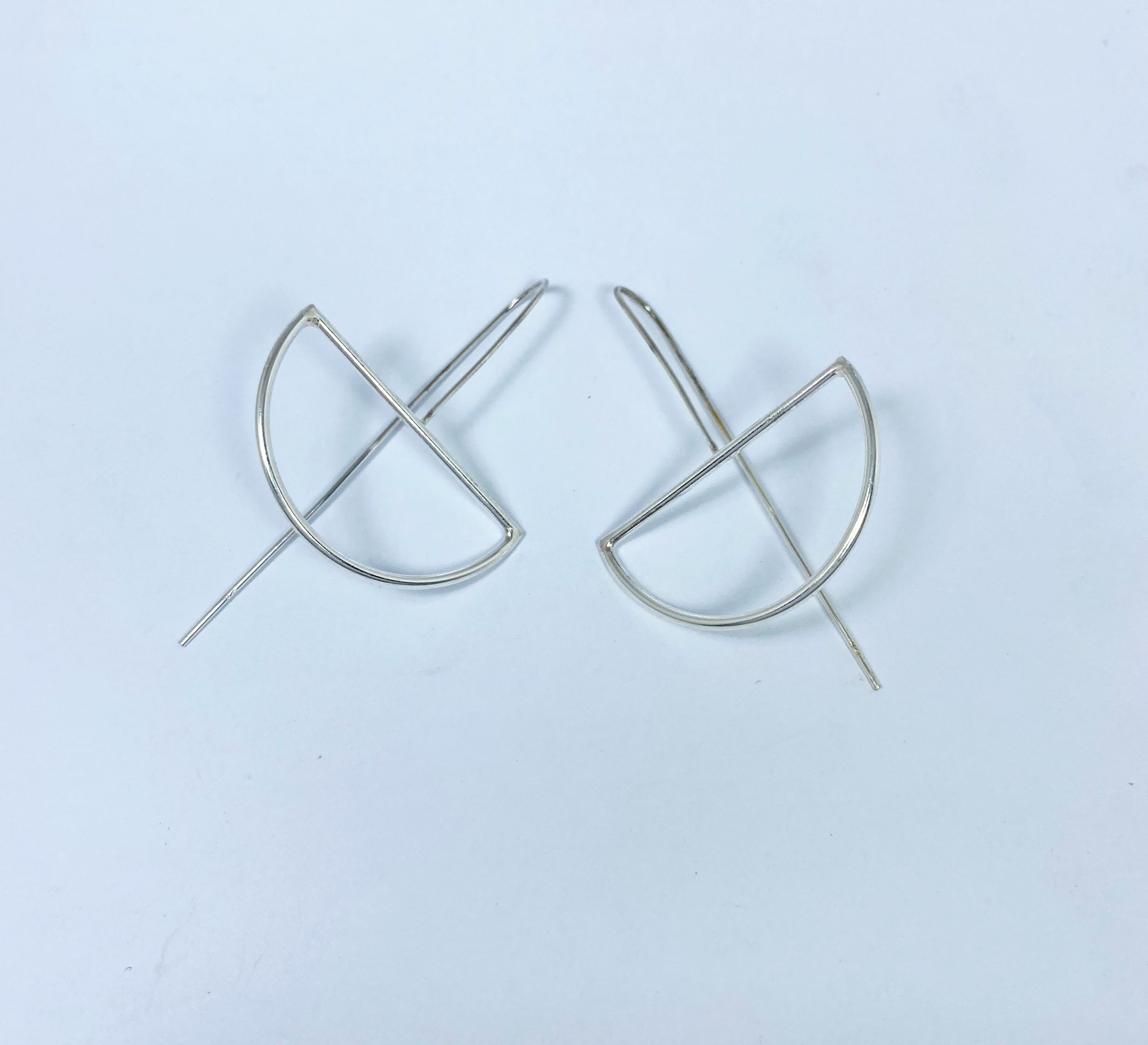 Pair of minimalist silver half-moon threader earrings.