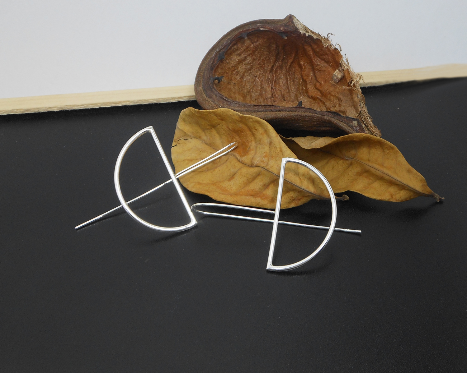 Detailed view of silver half-moon threader earrings with natural accents.