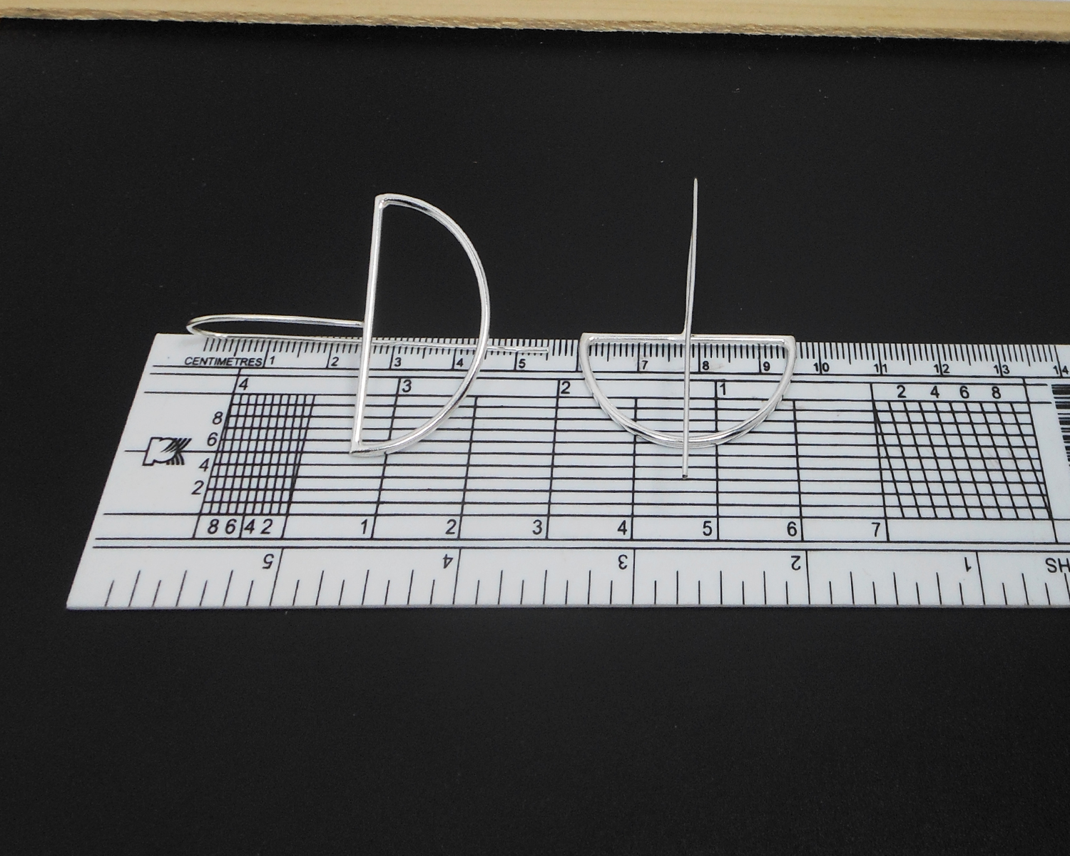 Silver half-moon threader earrings shown with a measuring tool for size reference.