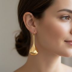 A model wearing long, gold-plated teardrop threader earrings.