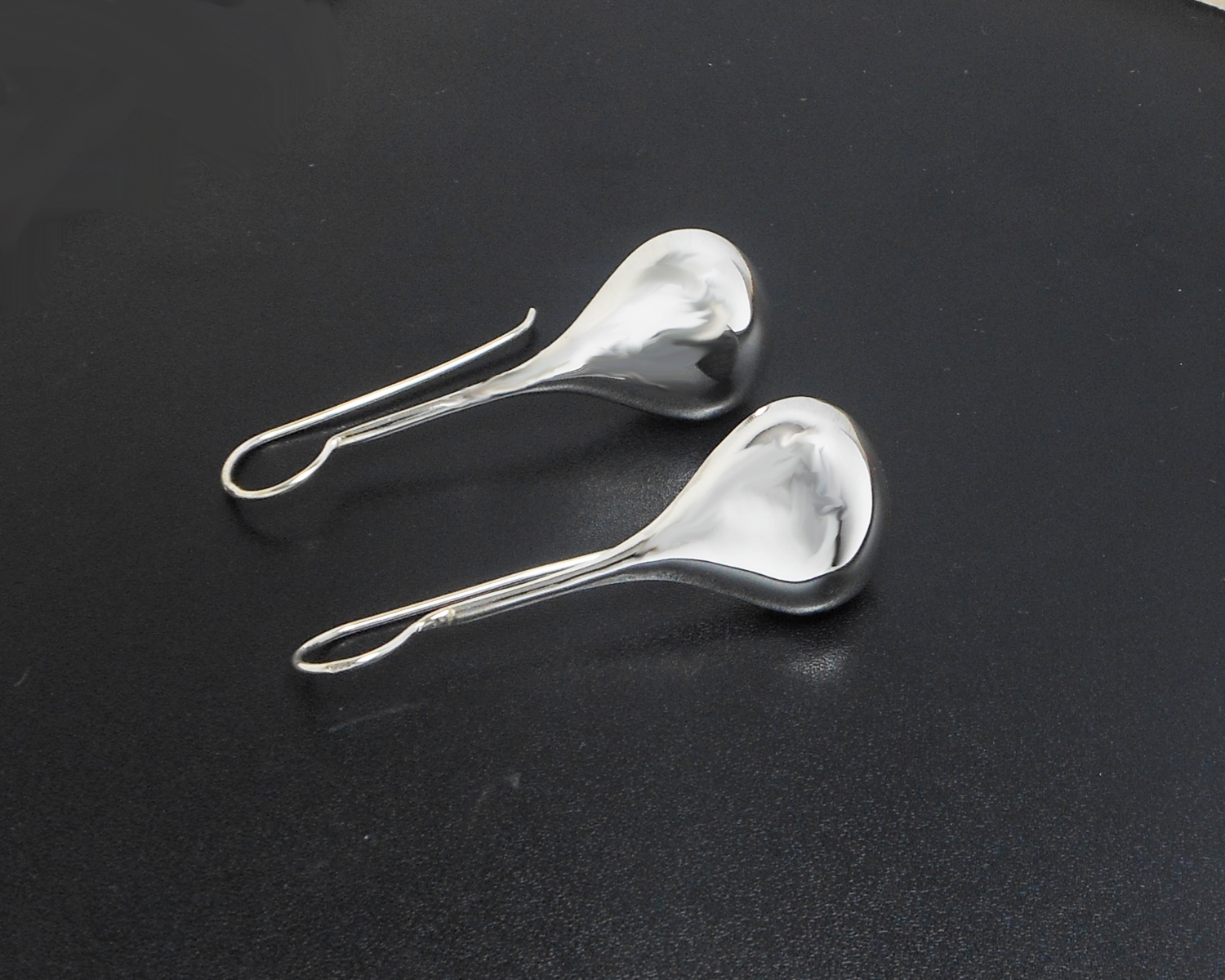 Pair of long teardrop threader earrings displayed against a dark background.