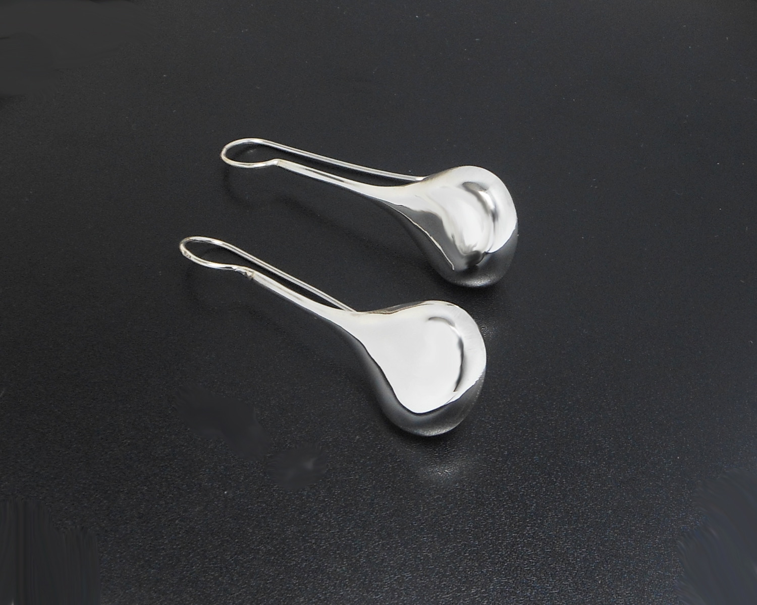 Angled view of long teardrop threader earrings.