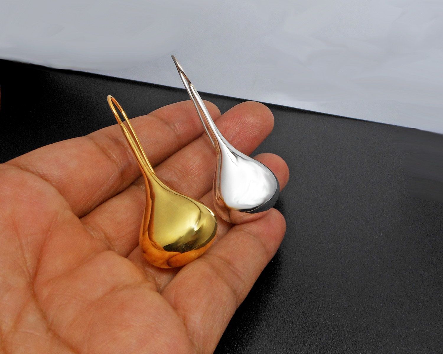 Handheld close-up showing the detail of long teardrop threader earrings.