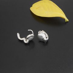 A pair of handcrafted 925 sterling silver leverback disc huggie hoop earrings resting on a dark surface next to a yellow leaf.