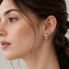 A close-up profile shot of a woman wearing the 925 sterling silver Greek Key arc earrings, highlighting how the perforated design looks when worn.
