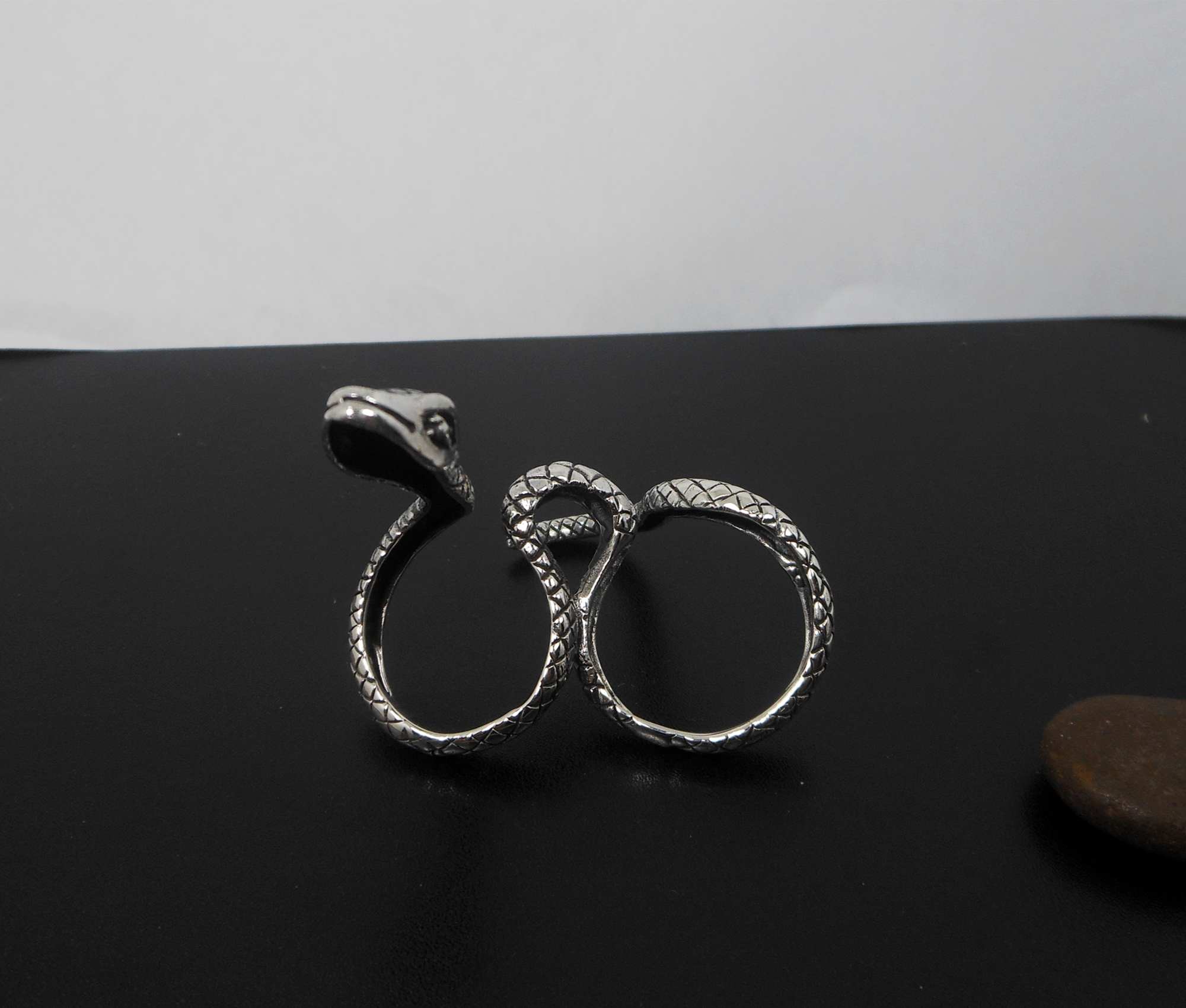 A handcrafted 925 sterling silver snake-shaped wrap ring with intricate texture, displayed on a surface.