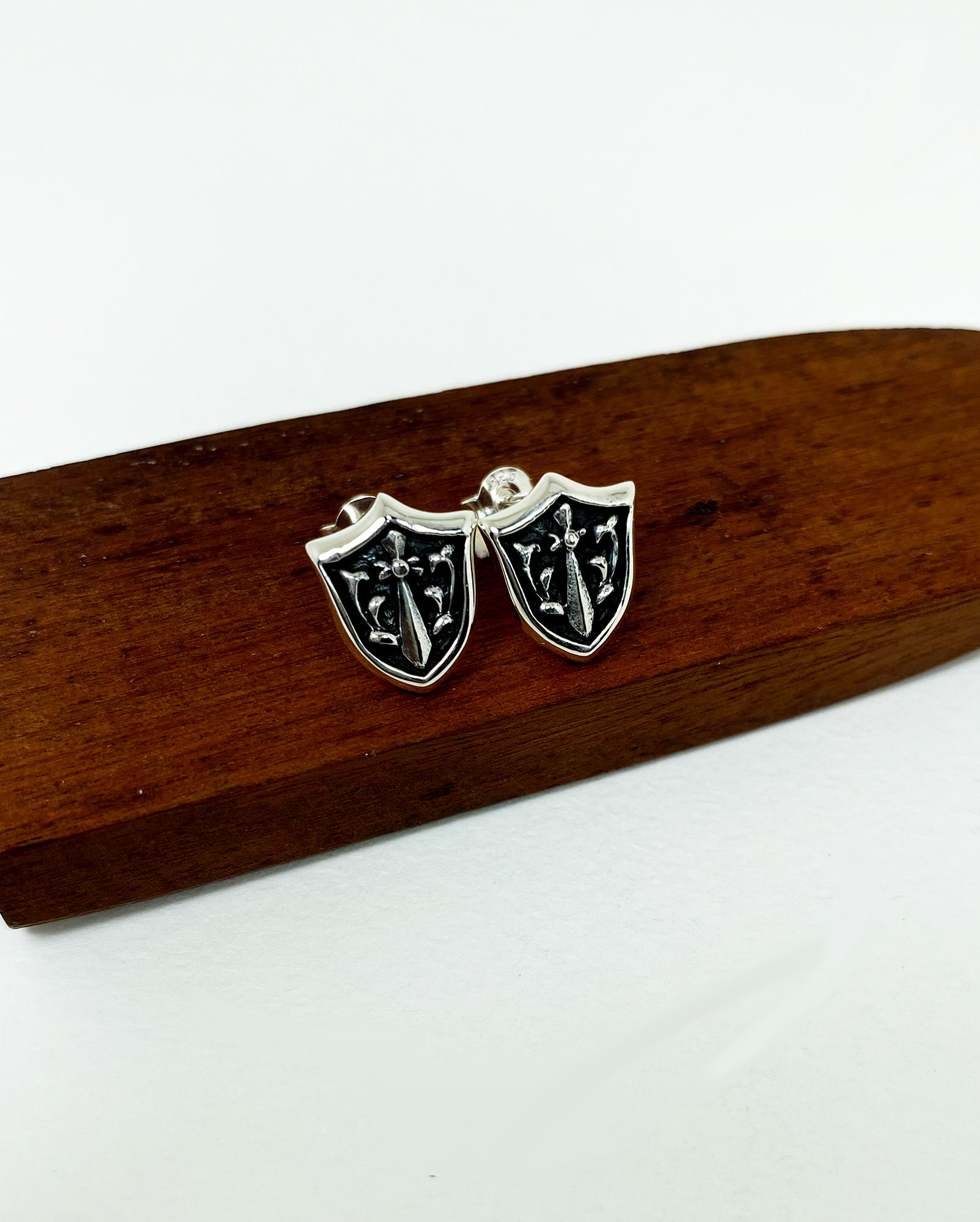 Side profile view of sterling silver sword and shield stud earrings.