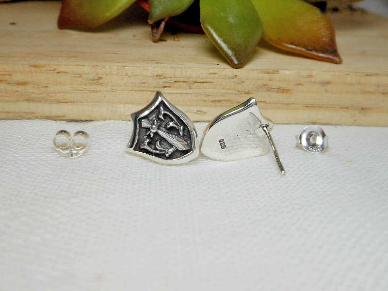 Sterling silver sword and shield stud earrings arranged for a product shot.