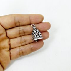 A person holding a handmade Thai filigree bell pendant in 925 sterling silver to show its size against a hand.