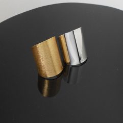 A handcrafted, wide flat band cuff ring made of 925 sterling silver, shown in both polished silver and matte gold-plated finishes against a rustic wood background.