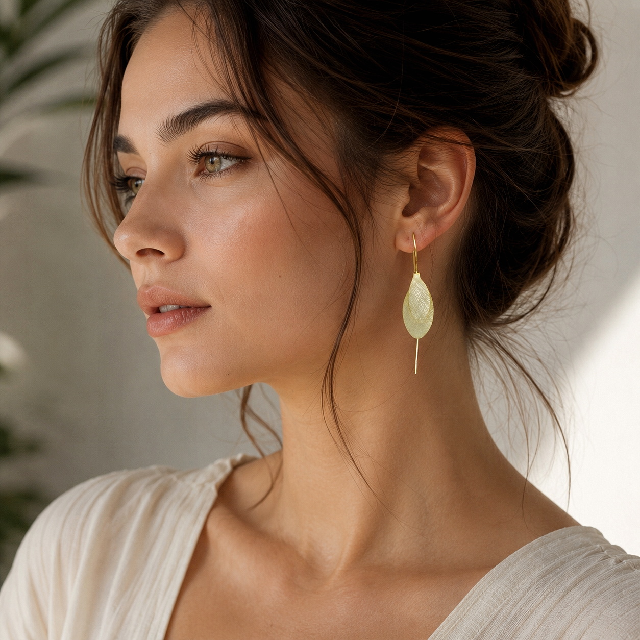 A model wearing gold plated, long, double-leaf threader earrings.