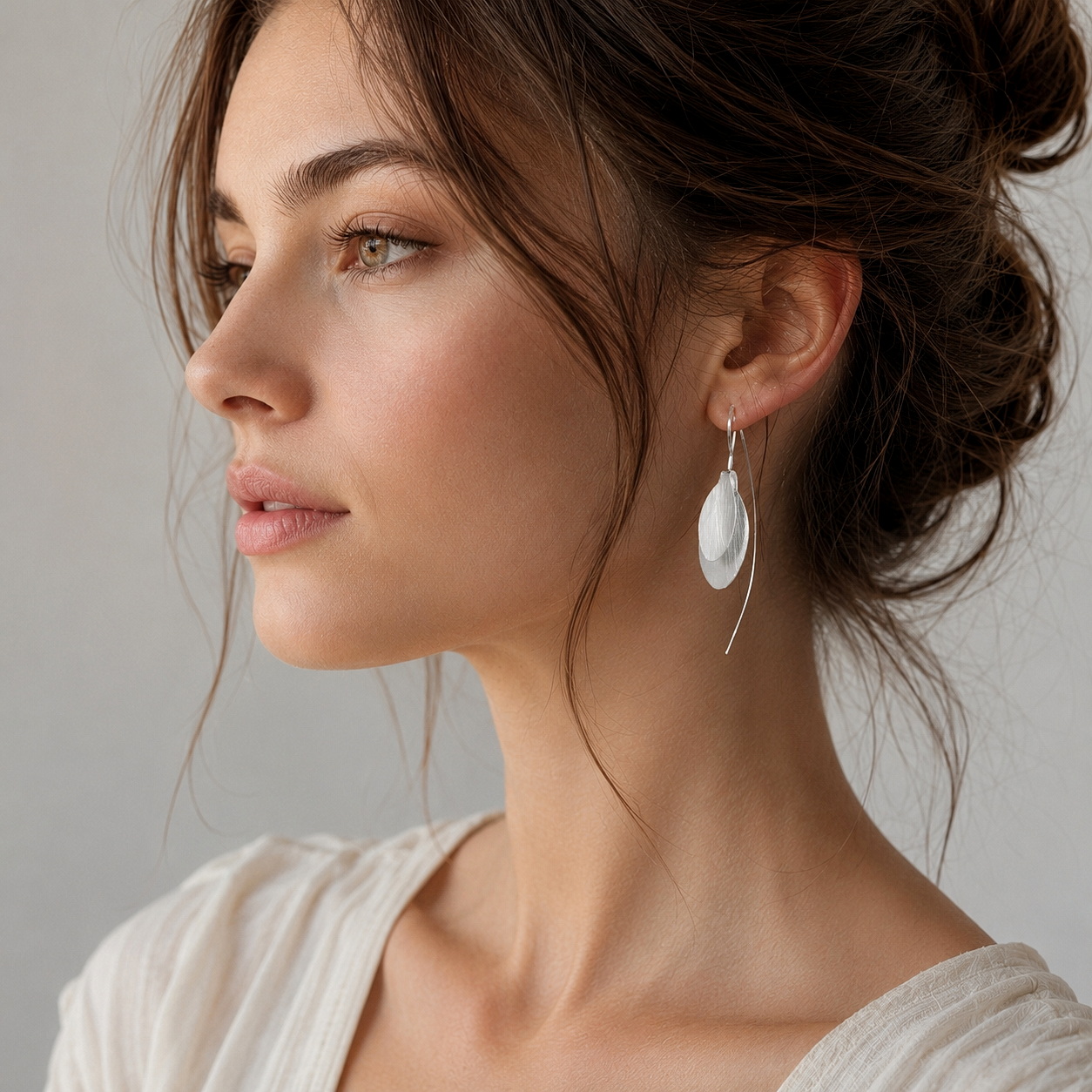 A model wearing silver, long, double-leaf threader earrings.