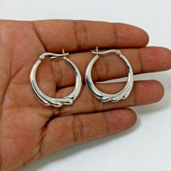 A pair of handcrafted 925 sterling silver hoop earrings featuring a unique puffy, textured flower-inspired design, displayed in a hand