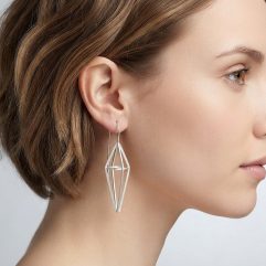 Profile of a woman wearing a geometric sterling silver threader earring with a cage design.