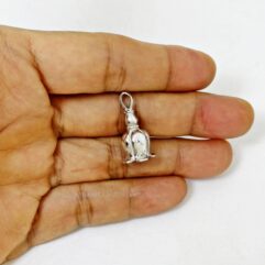 Hand holding a small 925 sterling silver lotus bud bell pendant against a plain white background.
