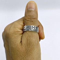 Back view of a man's hand showing a wide 925 sterling silver star and stripes band ring styled on the thumb.