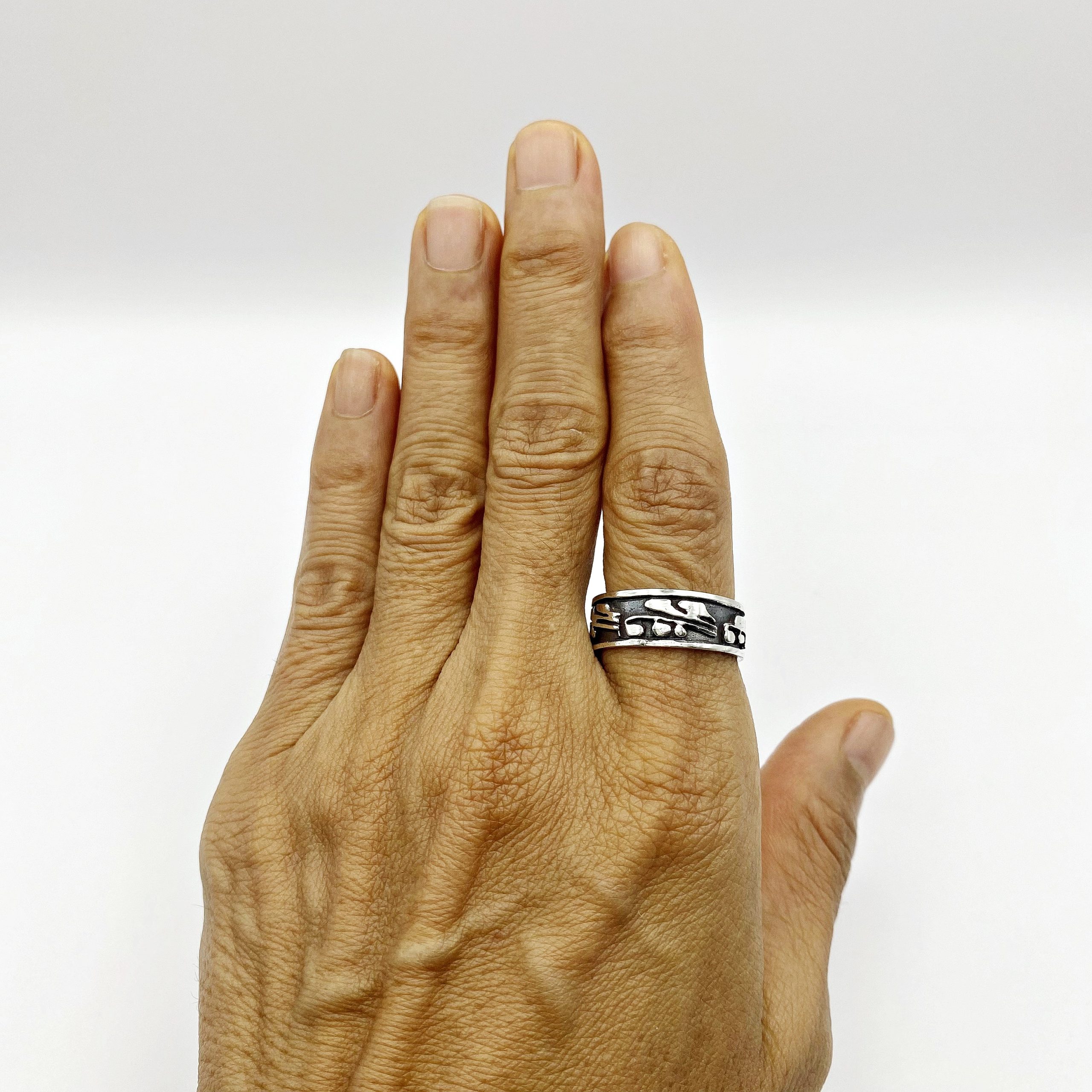 Front view of an open hand showing a sterling silver leaf ring worn on the index finger.
