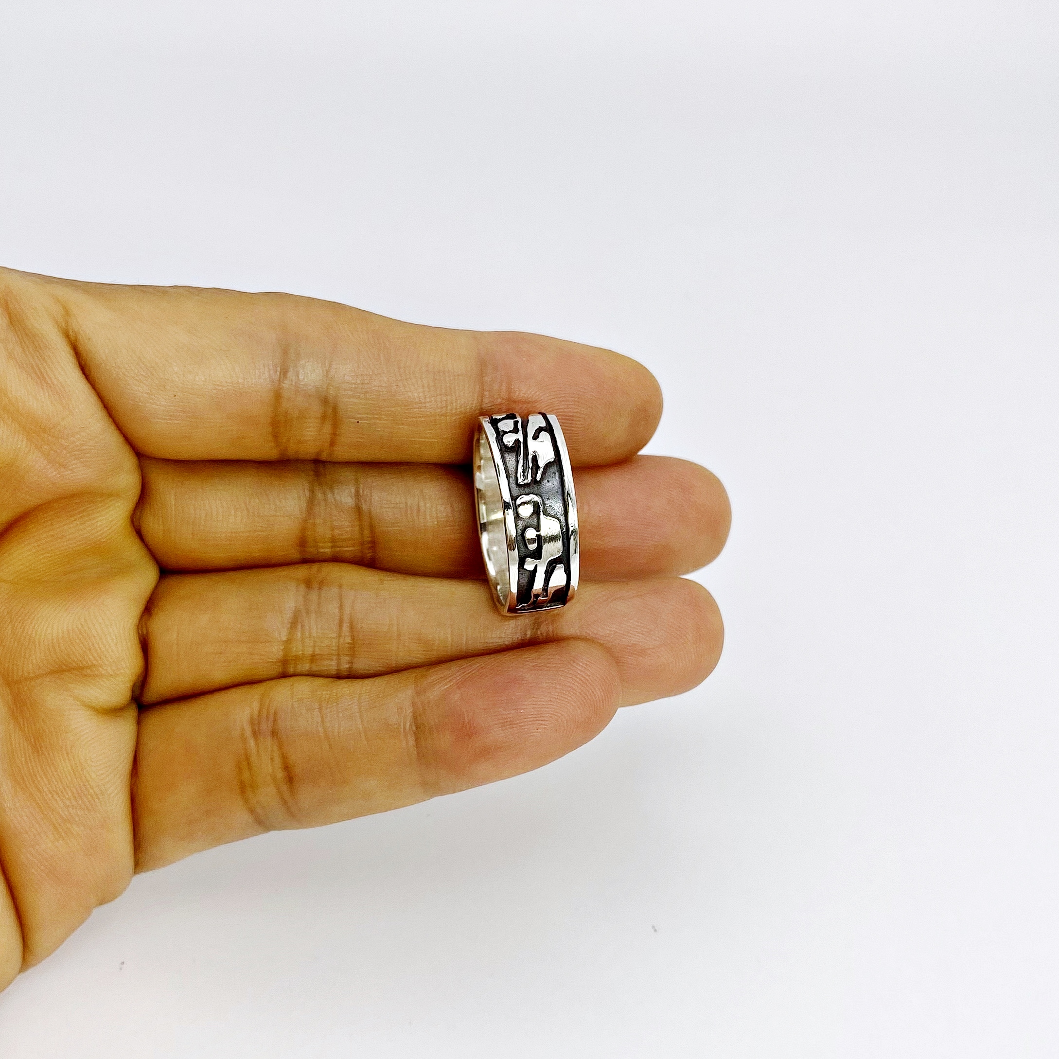 A wide textured silver band ring resting on the open palm of a hand.