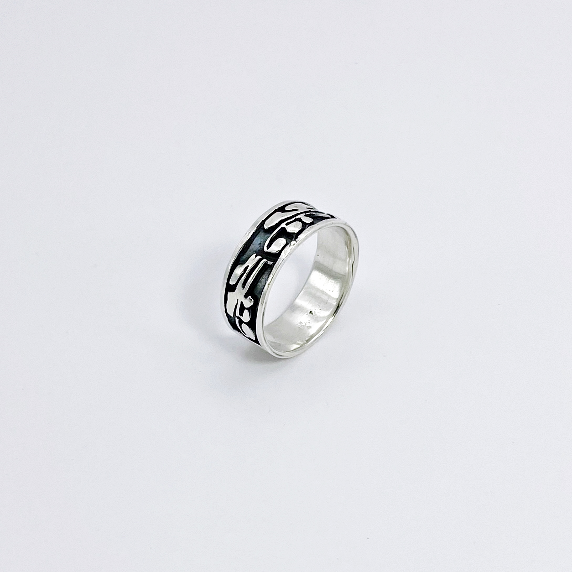 Right angle studio shot highlighting the dark oxidized details of a silver leaf ring.