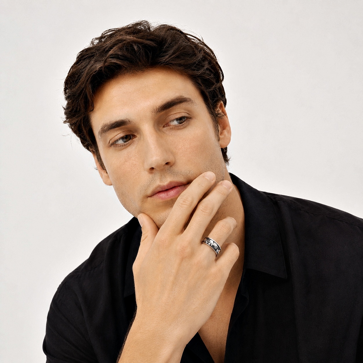 Casual portrait of a thoughtful man wearing a grey sweater and a silver ring.