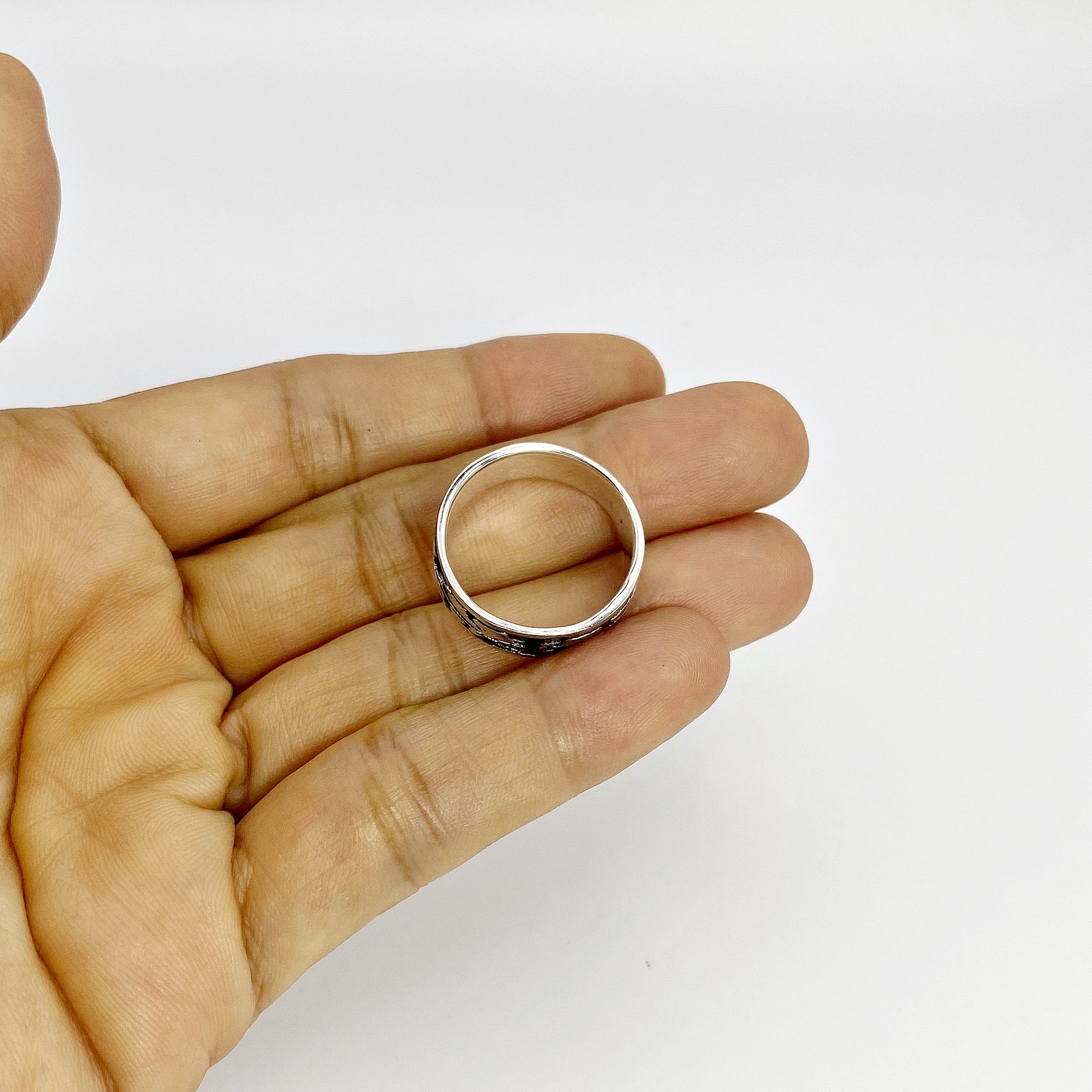Top-down angle of a hand with a silver leaf ring resting between fingers.