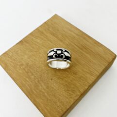 Frontal view of a vintage style oxidized silver Gothic ring placed on a natural wood block.