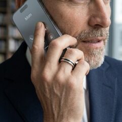 Lifestyle shot of a man wearing a black oxidized silver ring using a mobile phone.
