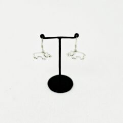 Main product image of the 925 sterling silver double-sided rhino dangle earrings facing each other, showcasing their bright, polished silver surface on a black T-bar stand..