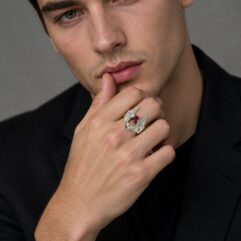 A lifestyle photo of a male model in a black shirt, posing to showcase the bat ring on his hand.