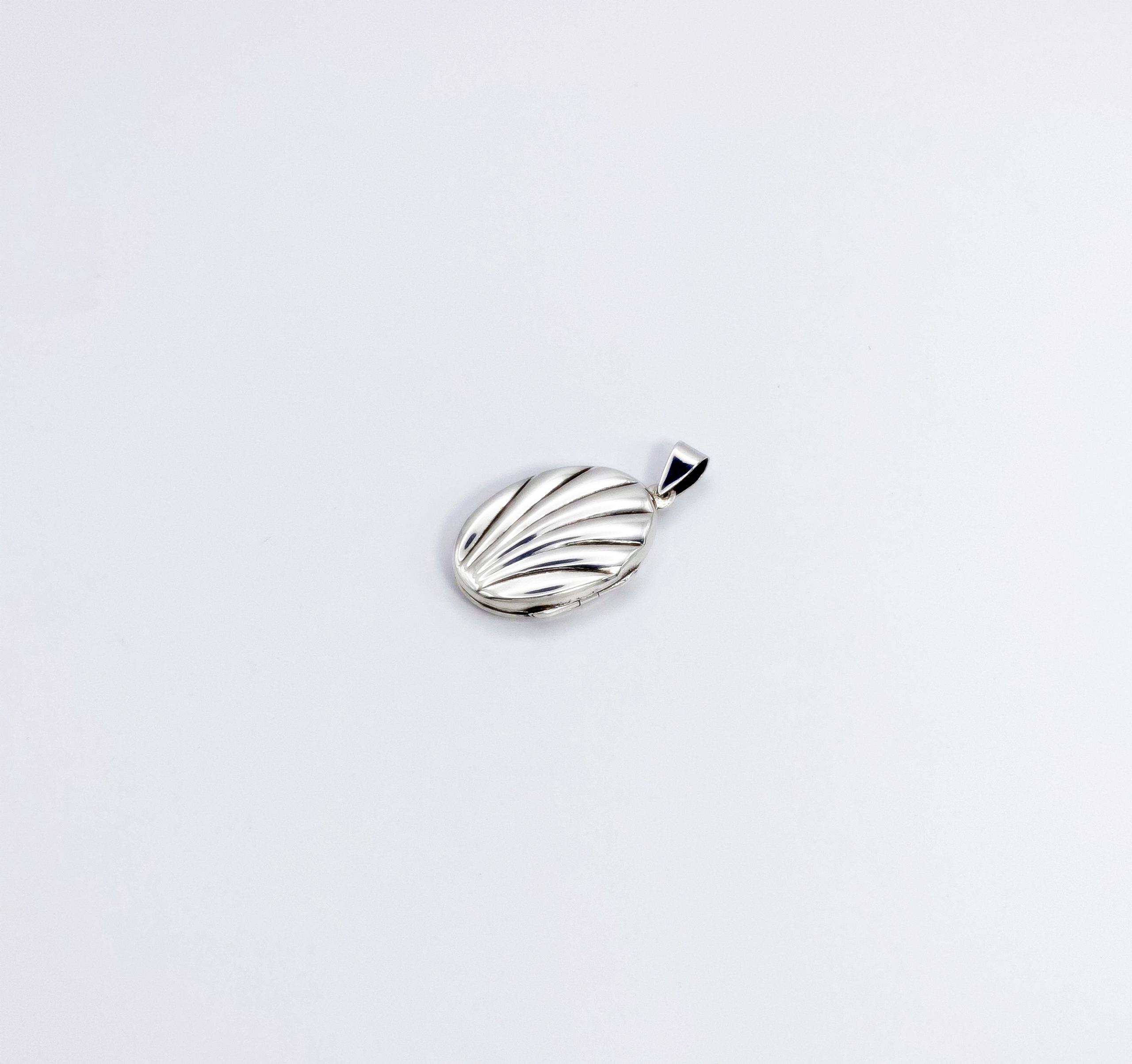 Side angle view of an oval sterling silver keepsake photo locket showing its depth, hinge, and thickness.