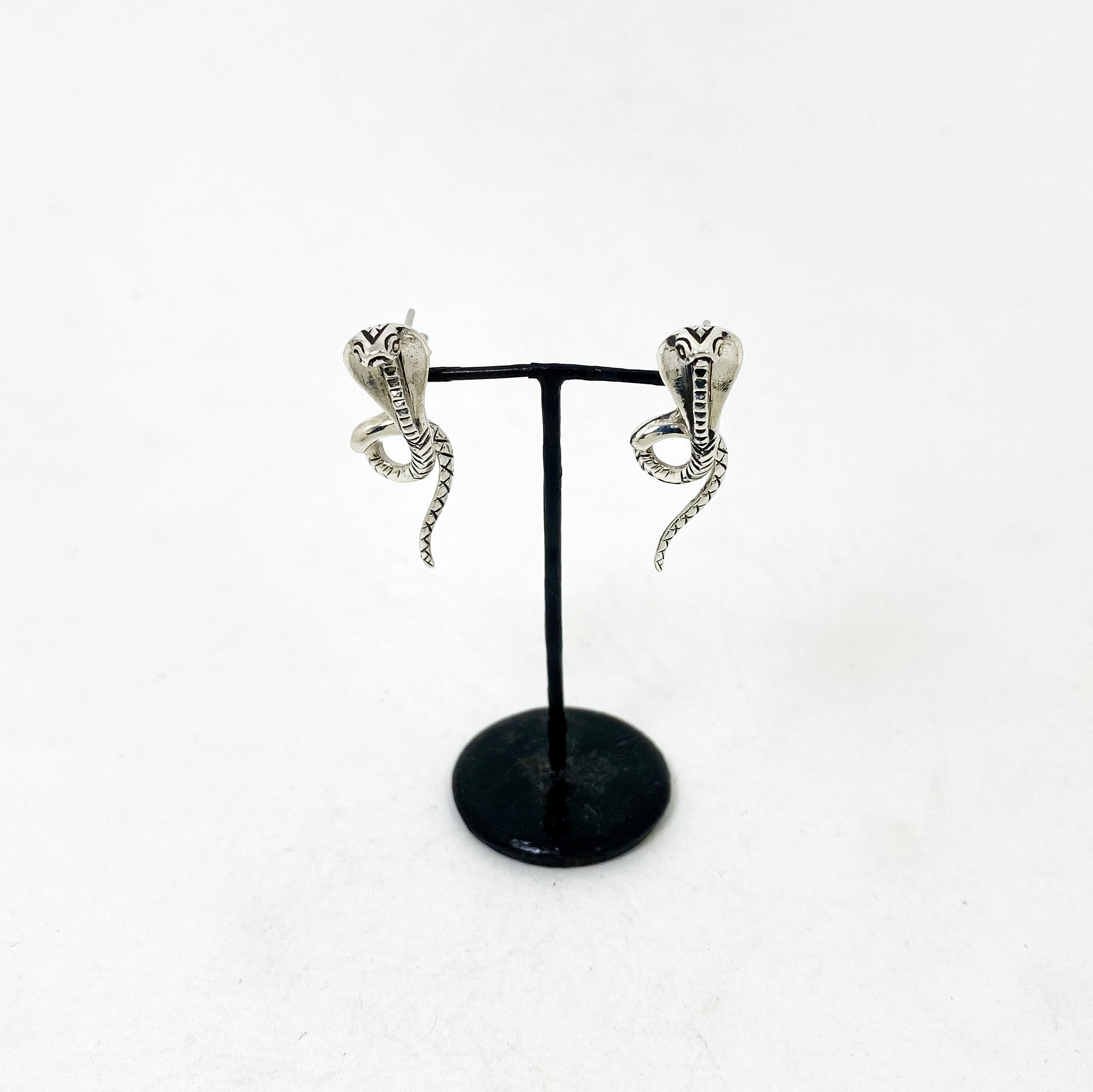 Handmade sterling silver king cobra snake earring jackets displayed on a small black T-bar stand.