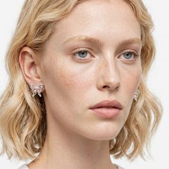 Close-up portrait view of model wearing handmade openwork butterfly stud post earrings in 925 sterling silver