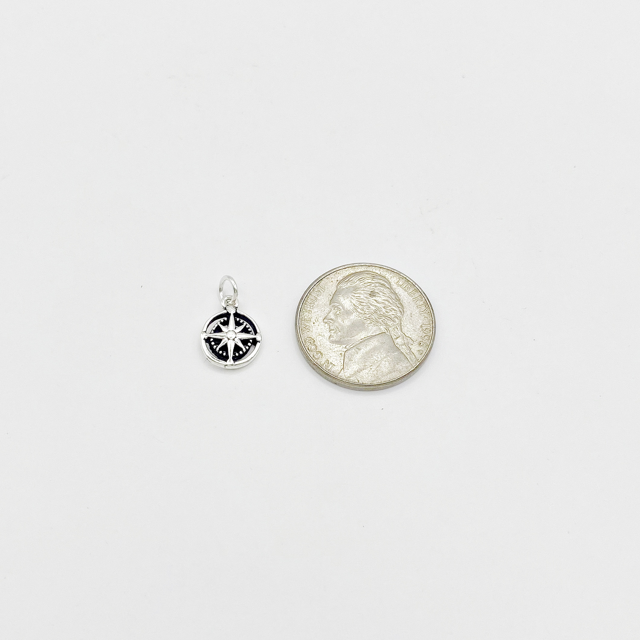 Sup Silver 925 sterling silver compass rose charm displayed next to a US nickel for size comparison.